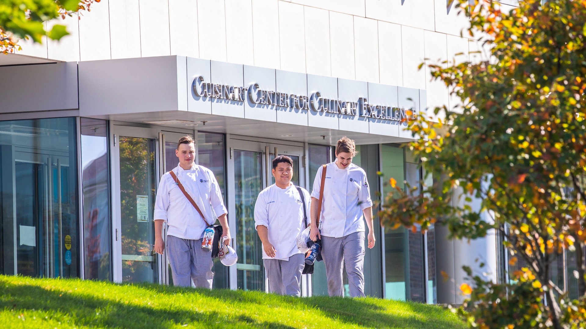 Trio of students walking in front of the Cuisinart Center for Culinary Excellence (CCCE).