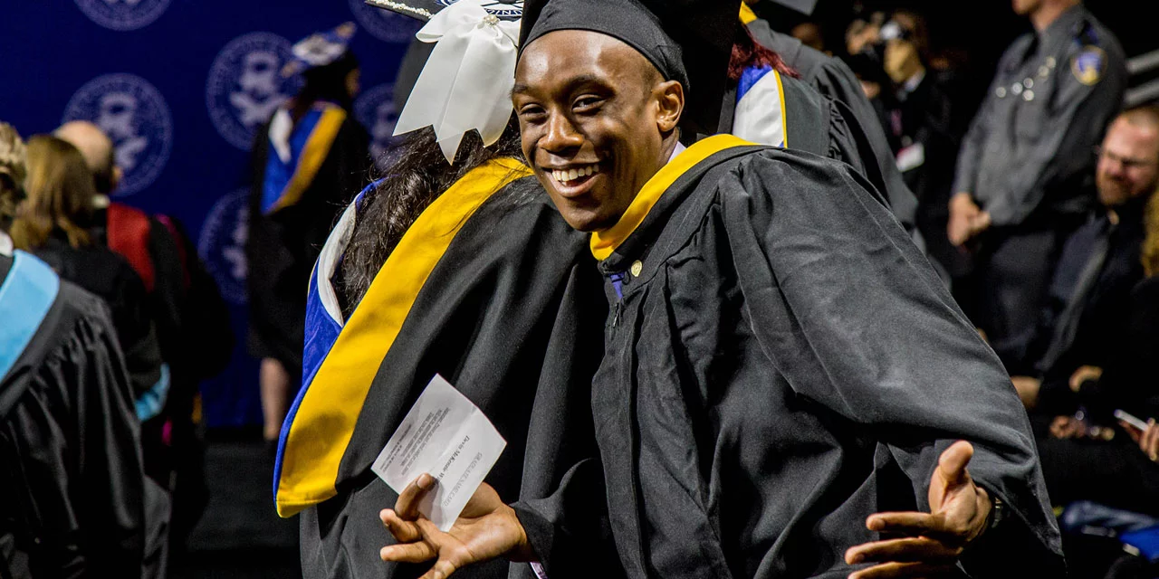 Students cheering and smiling after ceremony.