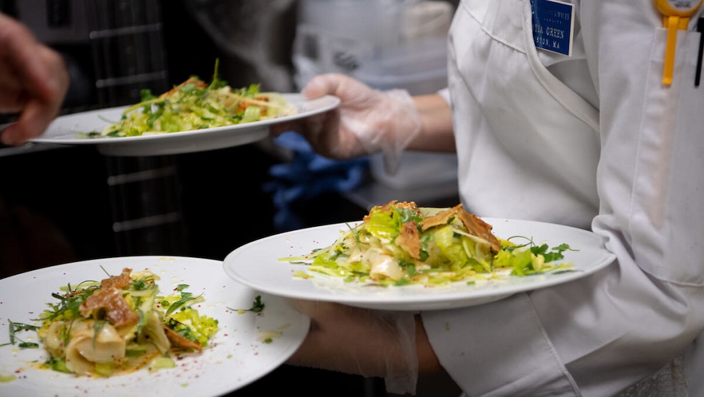 A student holding three plates of salad