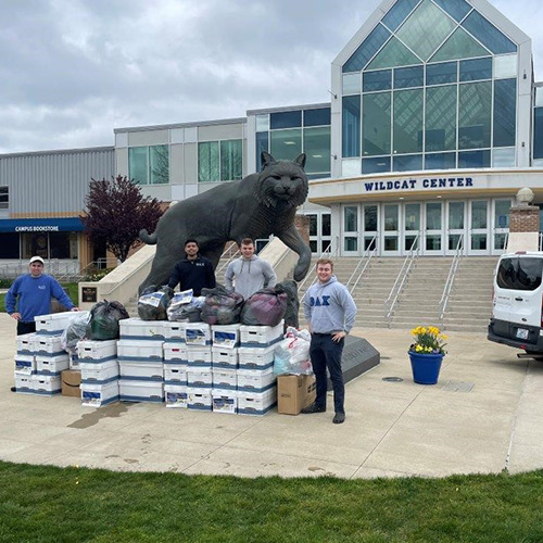 MEMBERS OF THETA DELTA CHI PAUSE FOR A QUICK PHOTO WHILE LOADING JWU-DONATED GOODS INTO A VAN FOR DELIVERY TO HOPE FOR UKRAINE