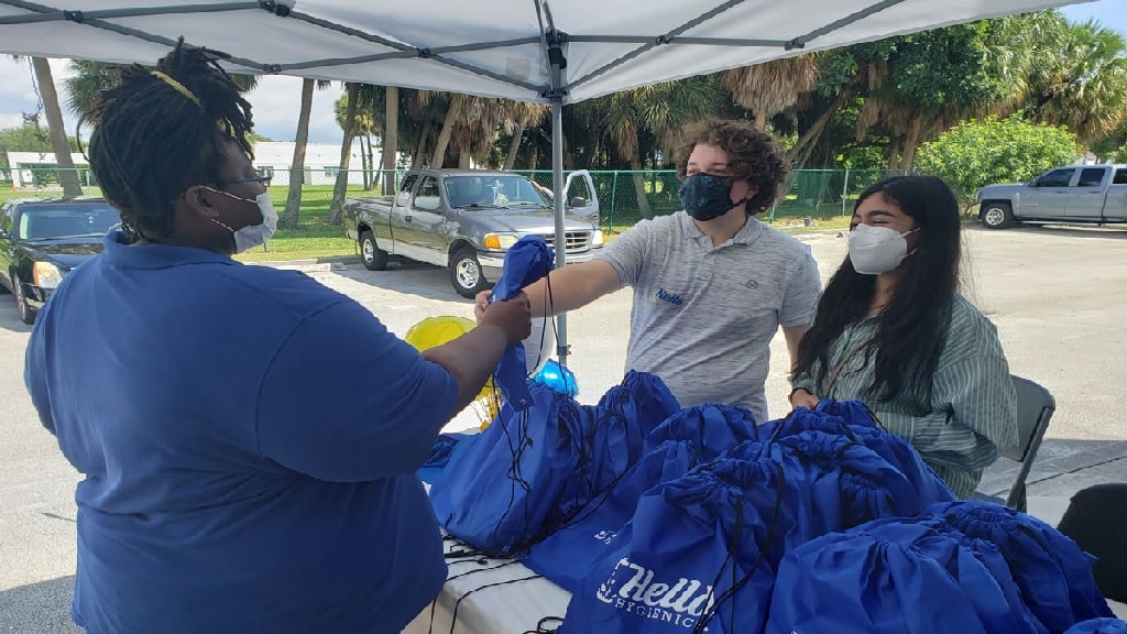 jonathan beres and nishah giving a woman a hello hygienics bag