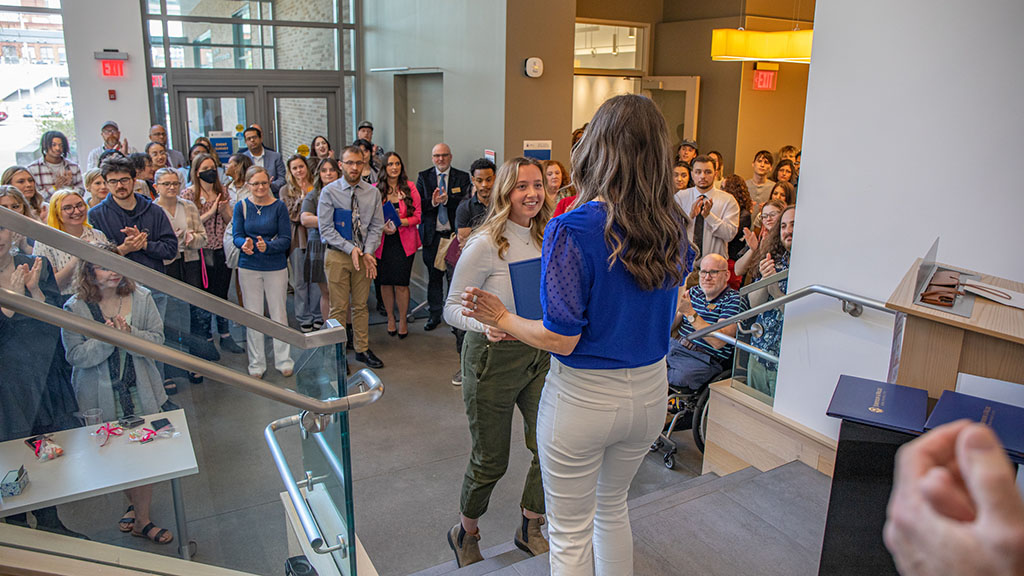 Professor Karyn Jimenez-Elliott handing a student their design certificate