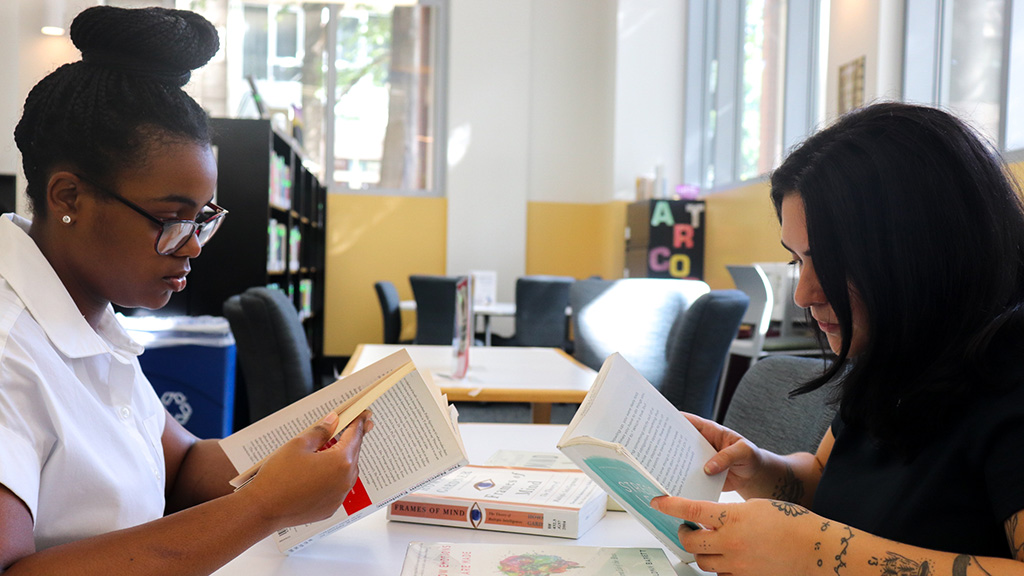 Gianna Marlow and a friend sitting at a table reading books