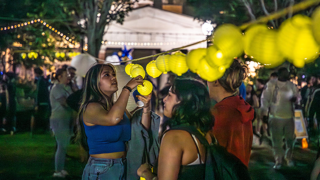 A girl hanging a lantern on a rope at night