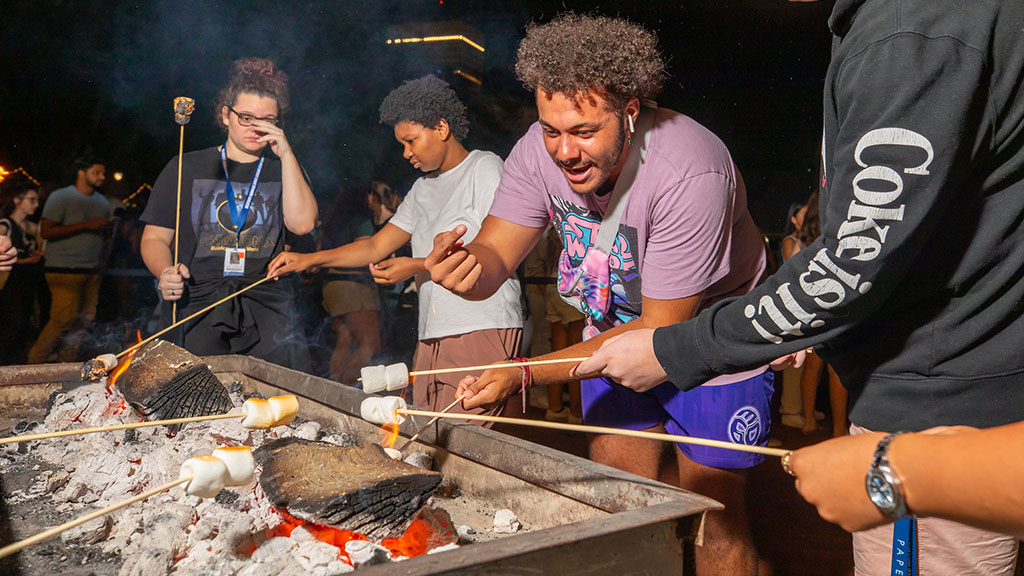 Students roasting marsh mellows over a fire