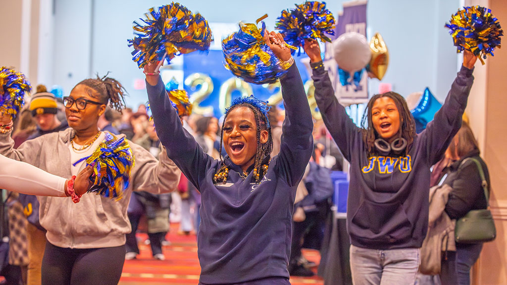 Three JWU students holding up pom poms