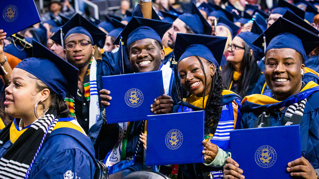 Smiling grads holding up their diplomas.