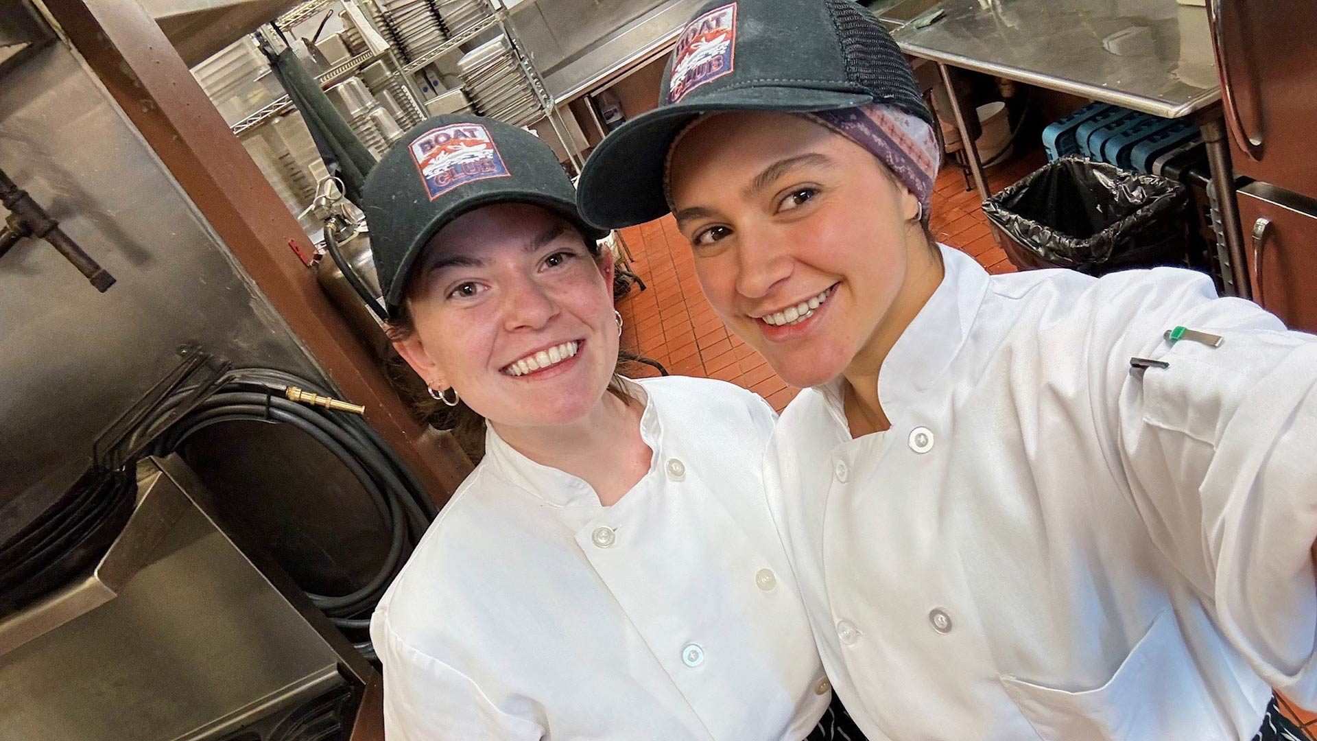 two young pause to take a selfie while working in a restaurant kitchen