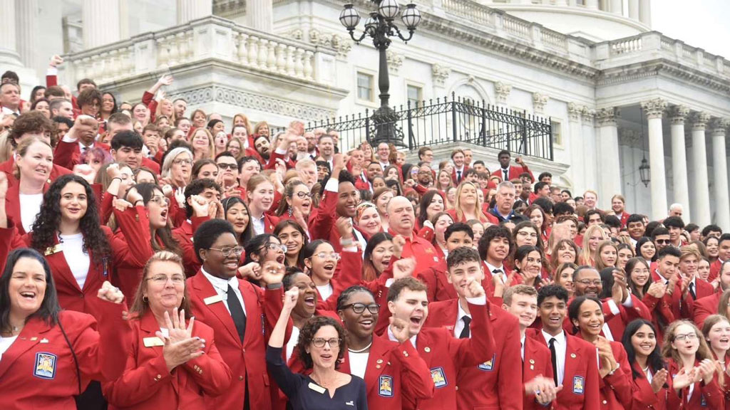 a group photo of SkillsUSA members wearing red jackets and posing in front of the State House