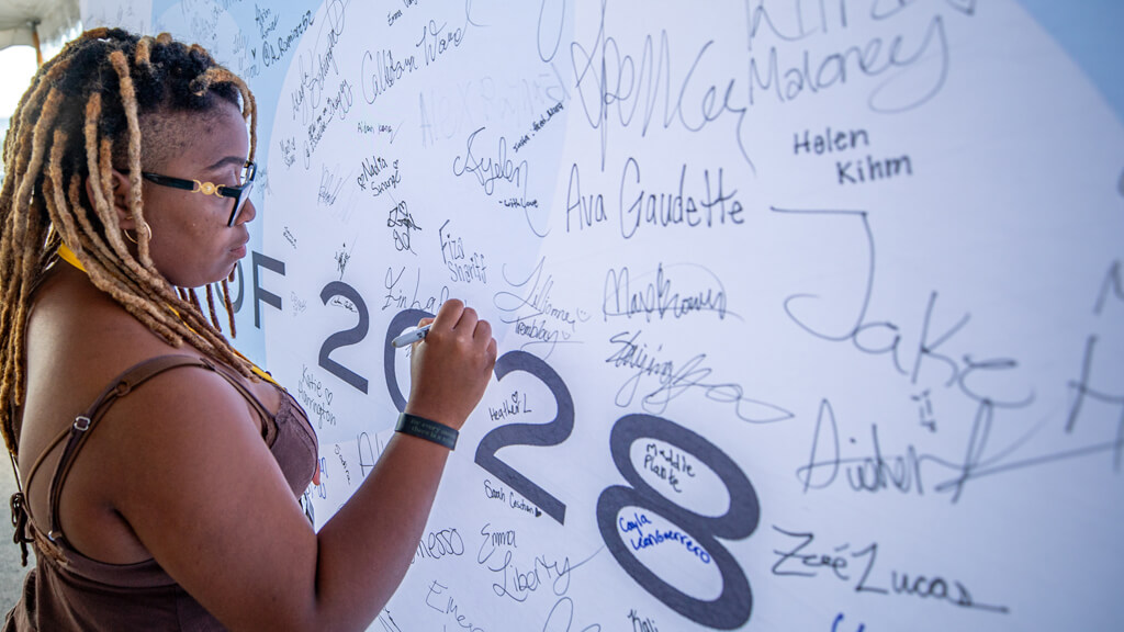 Fin adds her name to the class of 2028 signatures