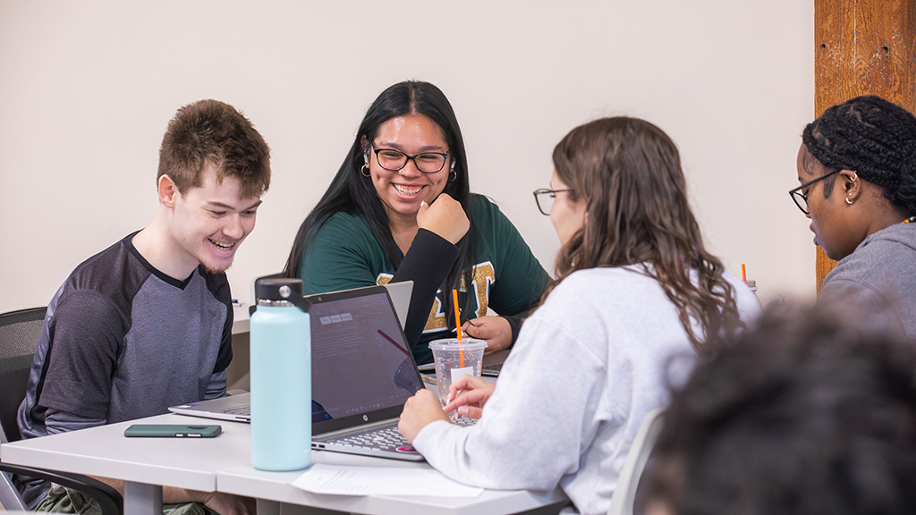 A group of students laughing while working together in a classroom