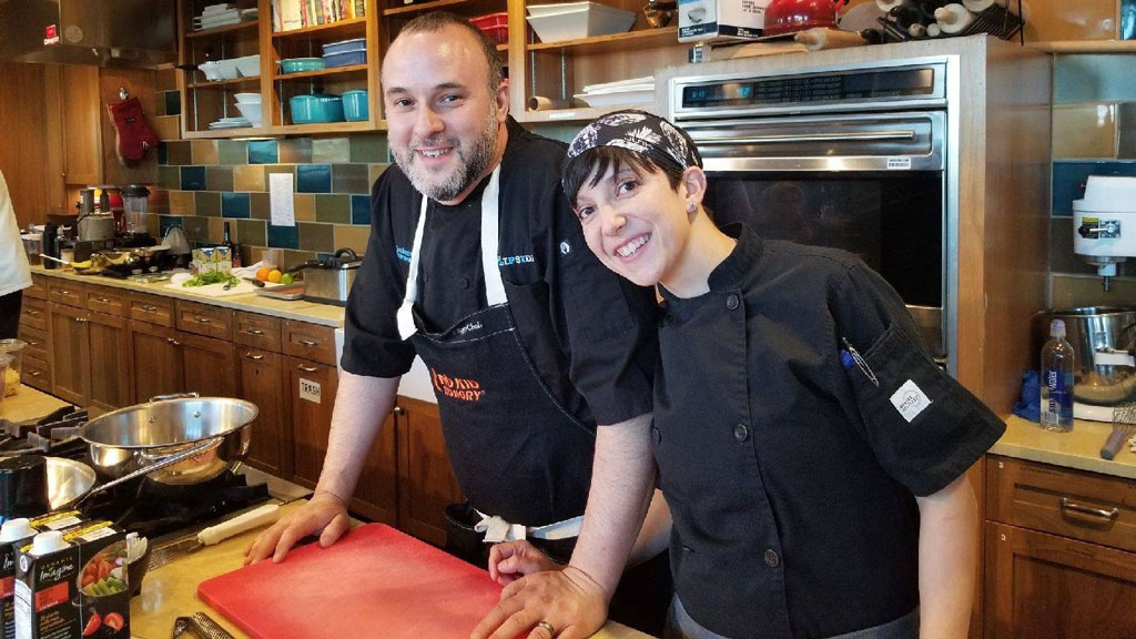 photo of Jon Fortes '97 and Amy Fortes '10 posing behind the counter of one of their eateries