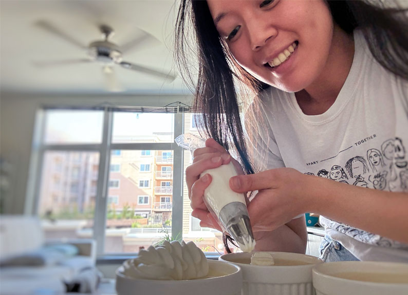 Terrene Huang '28 piping pastry cream in her kitchen.