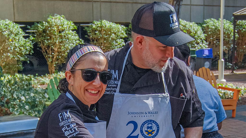 Two chefs wearing 20th anniversary celebration aprons.