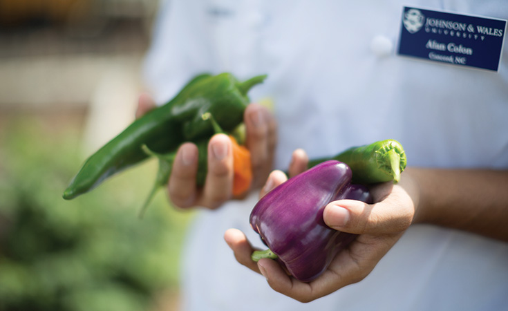 JWU students holding vegetables that they picked from a garden on campus.