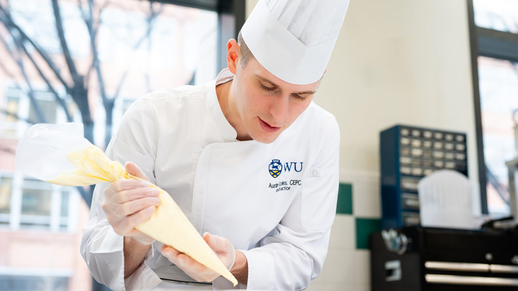 action photo of Austin Scoles '18 decorating with a pastry bag
