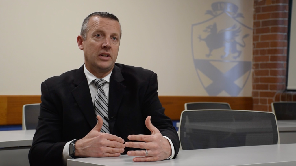 action photo of Stephen Riccitelli sitting at a table speaking