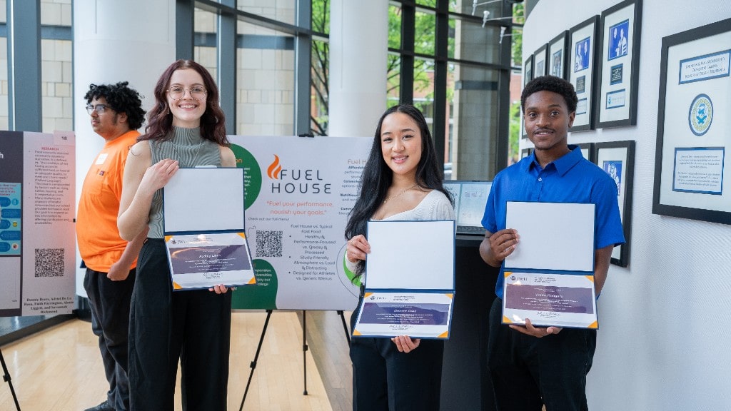 Audrey Linek ’25, Denise Diaz ’26, and Vante Rodger ’26 with their poster for “Fuel House: Healthy Fast Food for College Athletes.” 