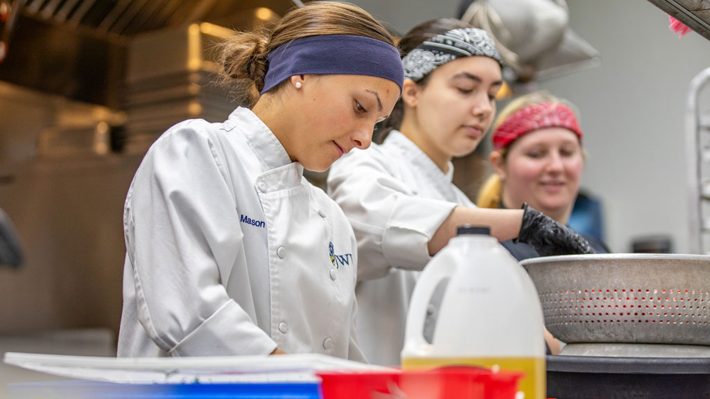 Olivia Mason ’26 (L) and Angela Dumford ’25 prepping in the kitchen.