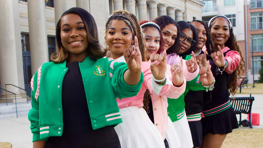 Women standing in a line doing their sorority sign with their hands