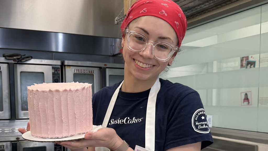 Zoe Bayat '26 with her completed pink frosted Valentine's Day cake.