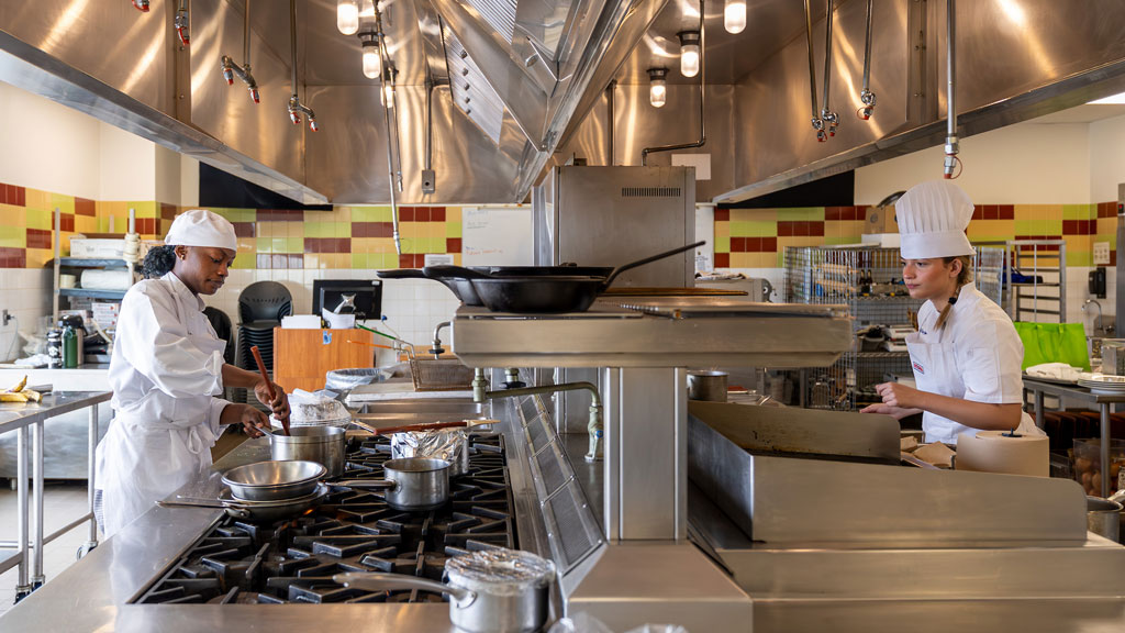 Aniyah Scarlett (left) and Paola Ruiz (right) prepping dishes in the CCCE production kitchen. 