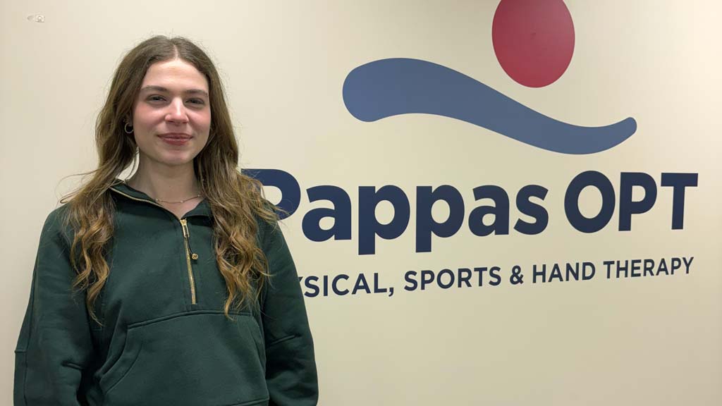 Kerra smiling at the camera with her internship name behind her, Pappas OPT Physical, Sports &amp; Hand Therapy