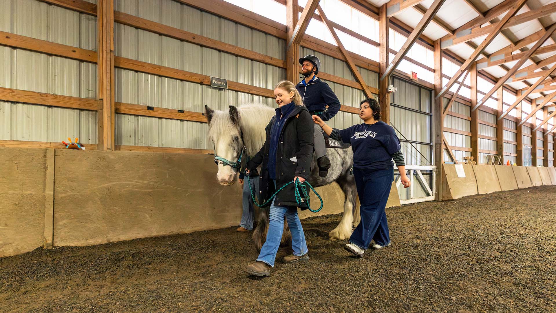 A man on a horse being guided by two women