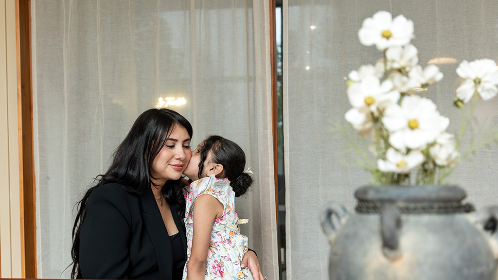 Andrea Cabrera '16, '18 MBA gets a kiss from her young daughter, Ava
