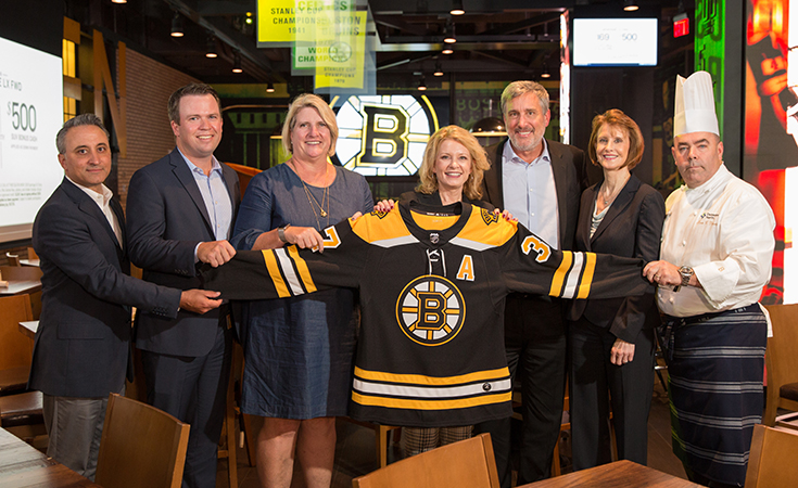 JWU and TD Garden staff holding a Bruins jersey